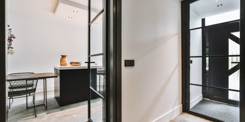 Stylish corridor with glass doors in black frames and a white wall